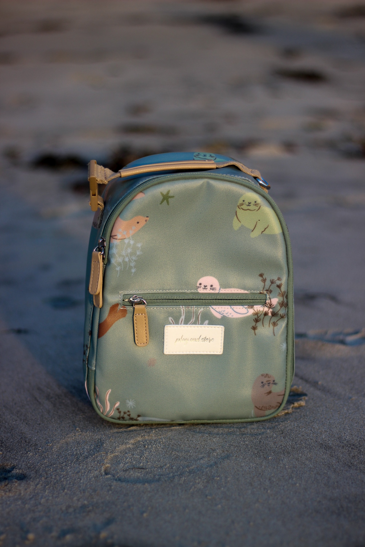 Mochila pequena verde com ilustrações de animais marinhos na areia