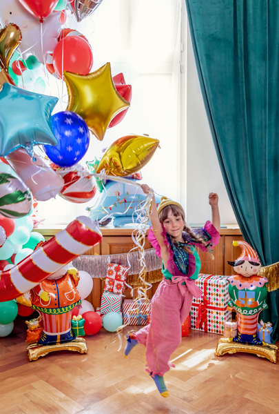 Balões coloridos, elfos infláveis e criança em festa numa sala interior