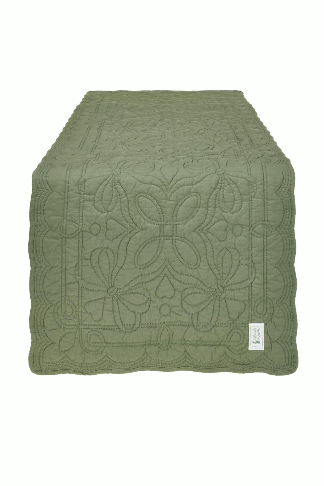 Colcha verde com padrão de quilting floral e etiqueta branca