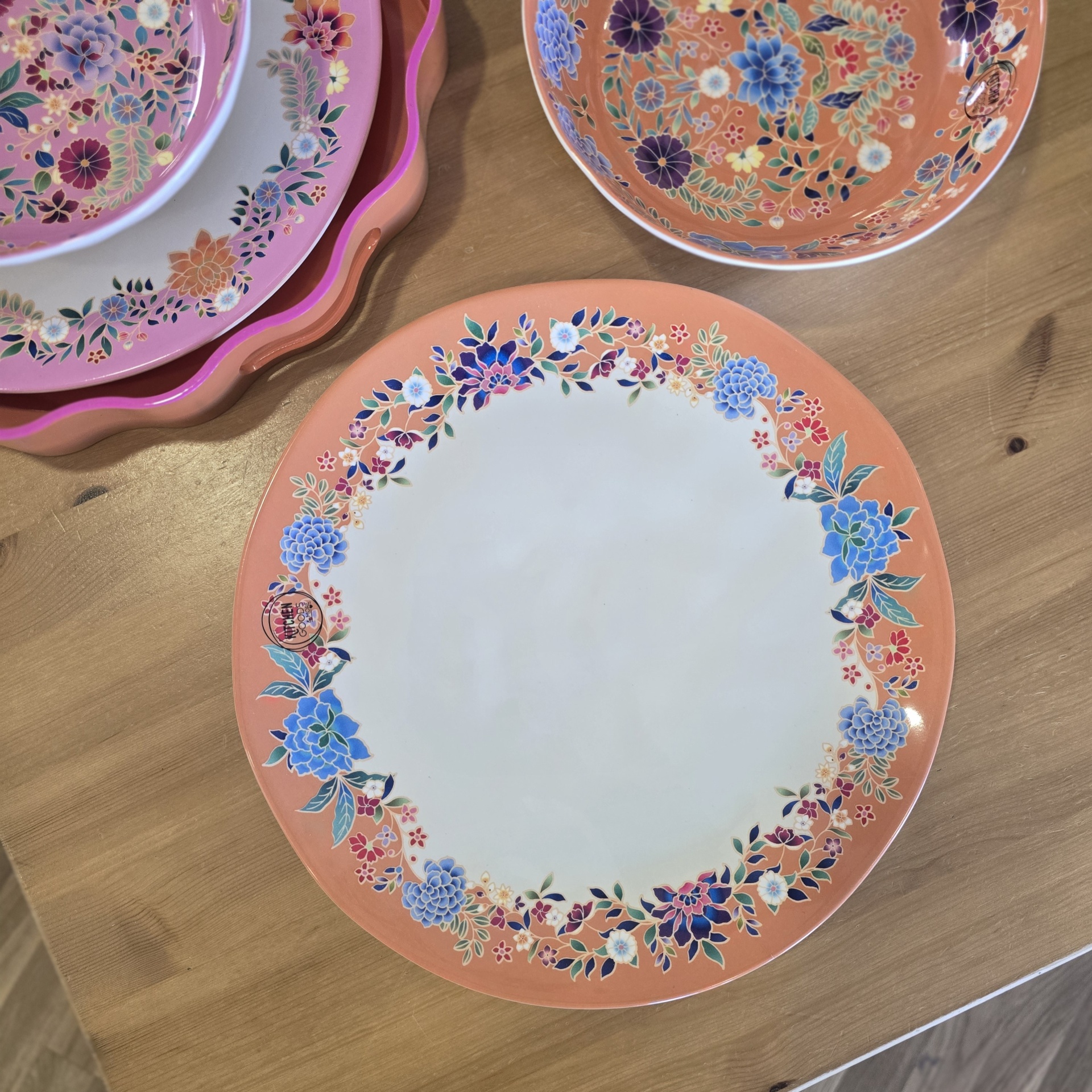 Conjunto de loiça cerâmica floral com pratos e tigela sobre mesa de madeira clara