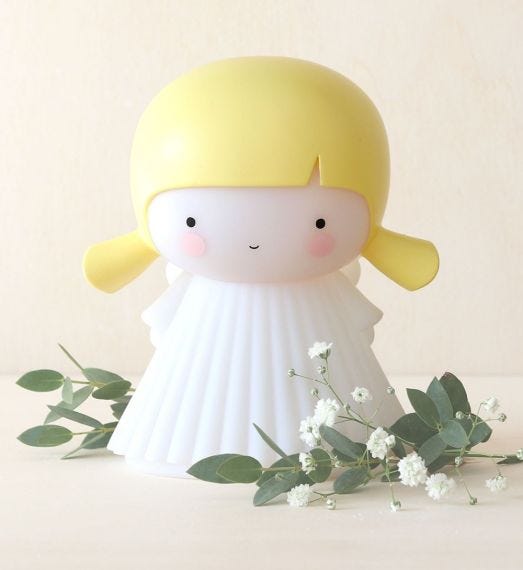 Figura decorativa com cabeça amarela e corpo branco em superfície clara com flores