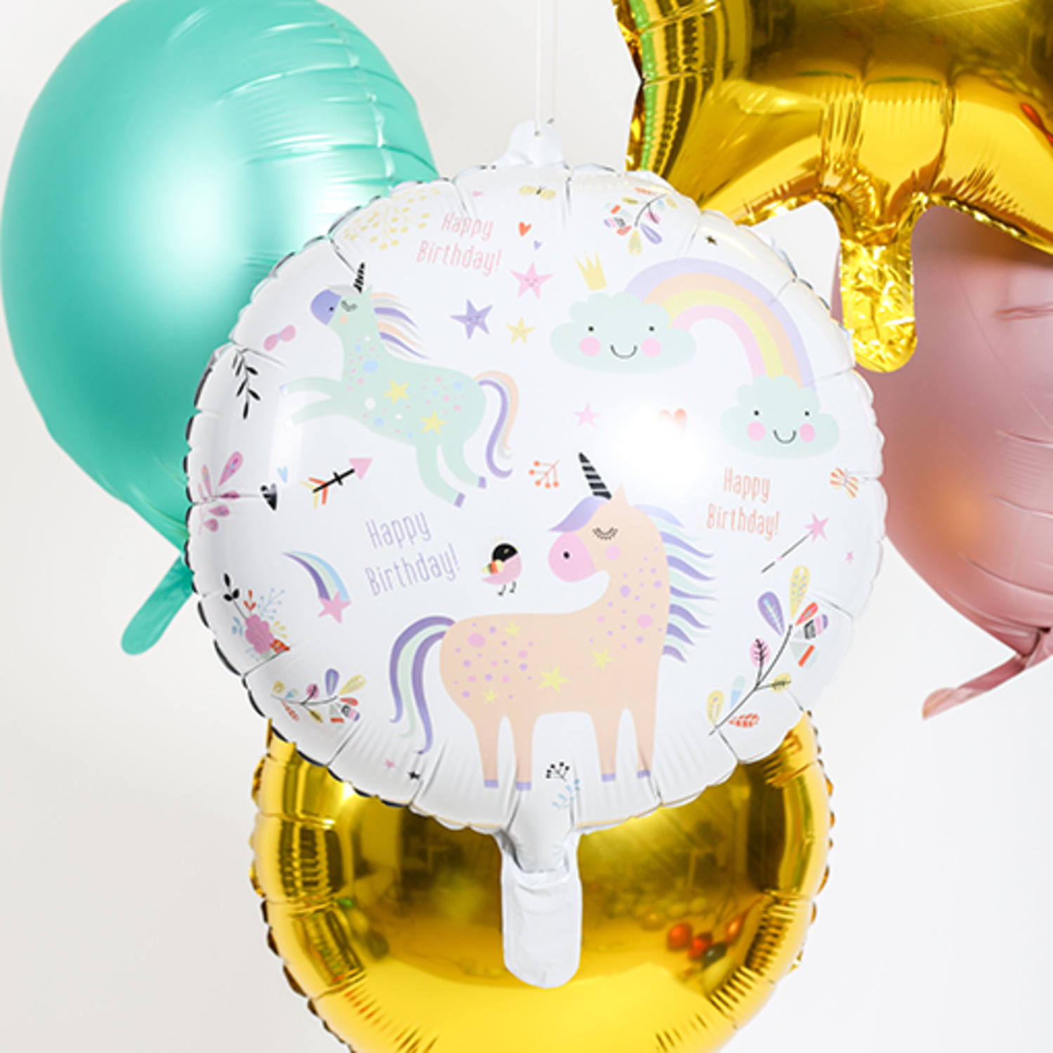 Balões metálicos coloridos com desenhos de unicórnios e texto Happy Birthday