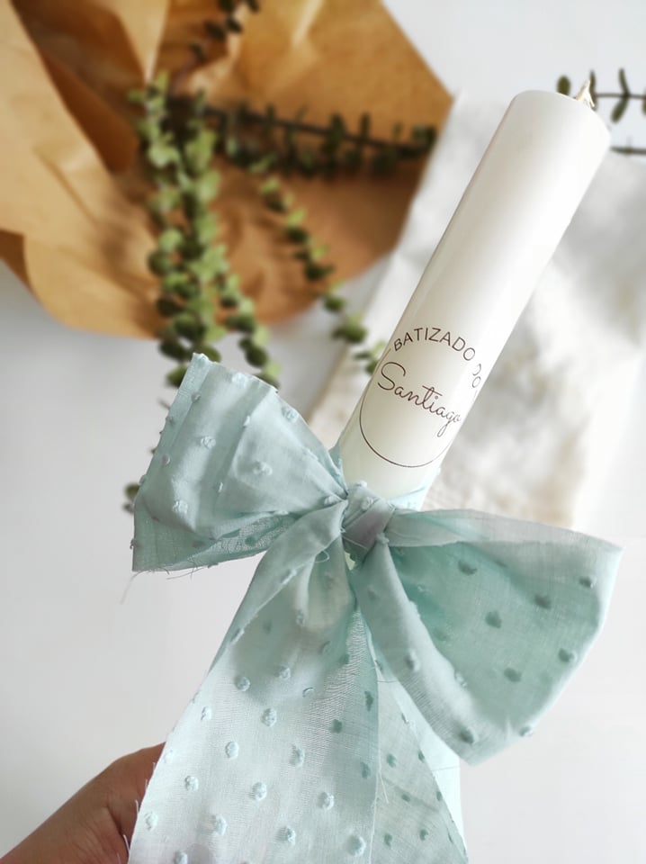 Vela branca decorada com laço azul claro e texto 'BATIZADO Santiago'