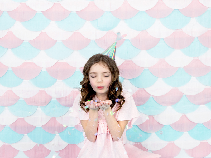 Menina com vestido rosa e chapéu de festa em fundo colorido de escamas