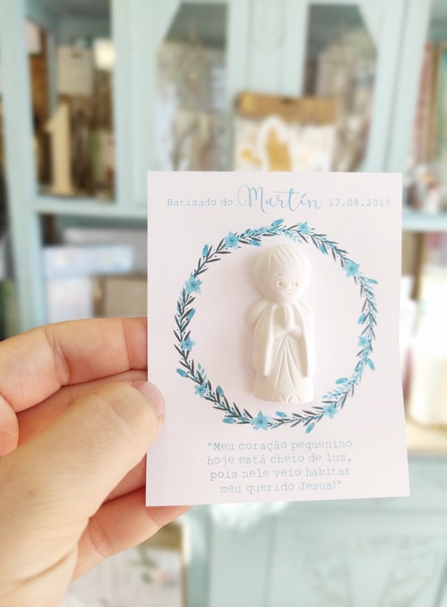 Cartão de batizado com figura em relevo de criança rezando e texto em português.