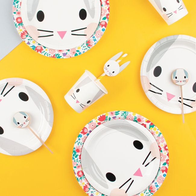 Artigos descartáveis com motivos de coelho para festa, sobre fundo amarelo