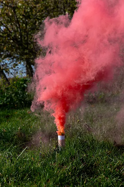 sinalizador de fumo vermelho a emitir humo em relva verde
