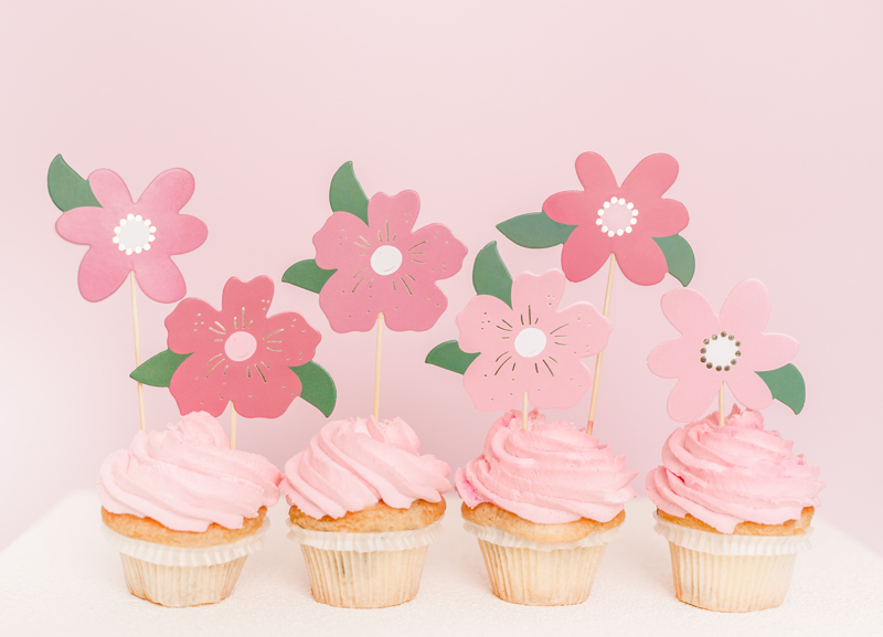 Quatro cupcakes com creme rosa e decoração de flores de papel cor-de-rosa
