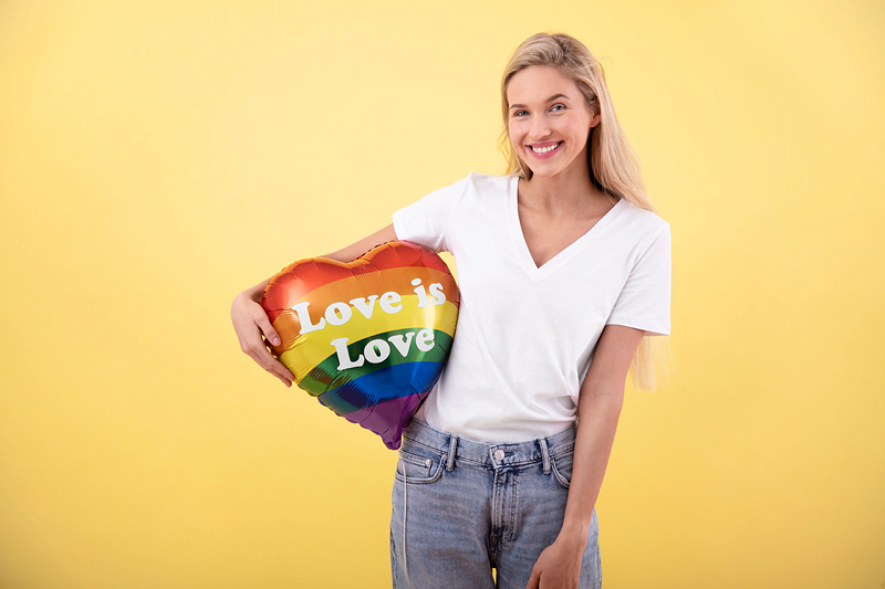 Mulher com balão em forma de coração 'Love is Love' colorido arco-íris.