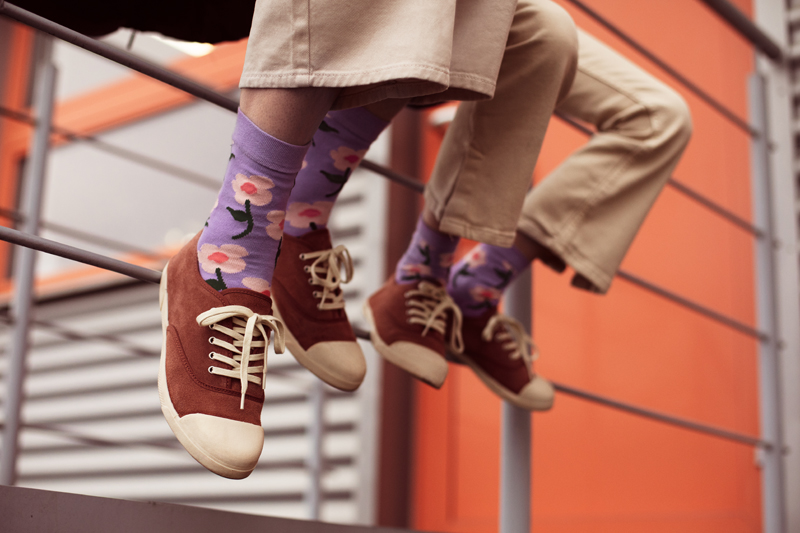 Sapatilhas castanhas com biqueira branca e meias roxas com flores