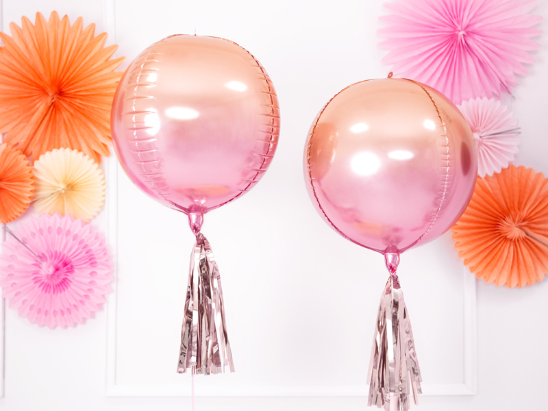 Dois balões redondos cor de rosa metálica com tassel prateado e decoração de papel colorida atrás