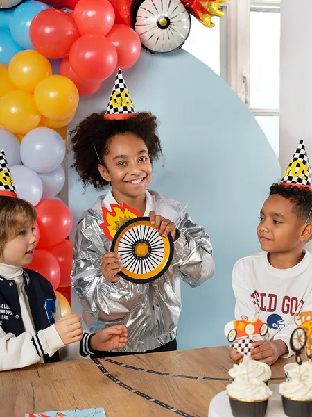 Crianças numa festa de aniversário com chapéus de festa e decorações de corrida automóvel