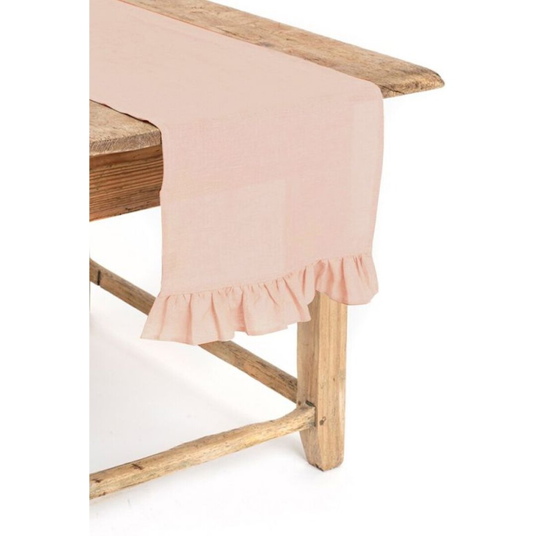 Caminho de mesa rosa claro com bainha franzida numa mesa de madeira rústica