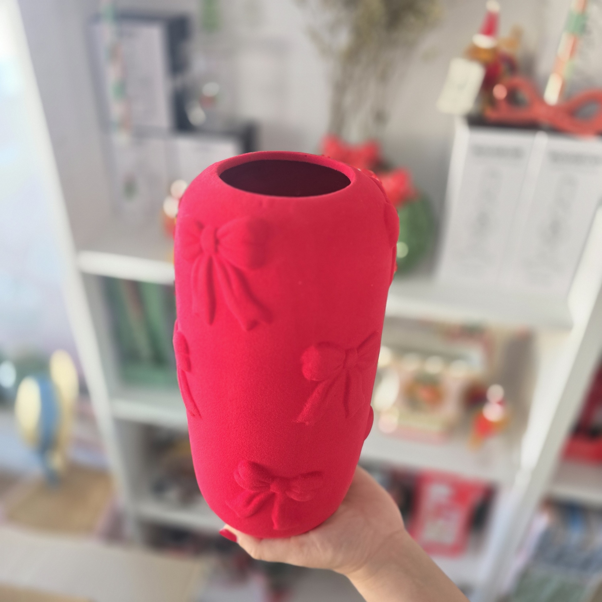Vaso vermelho com laços em relevo segurado à mão