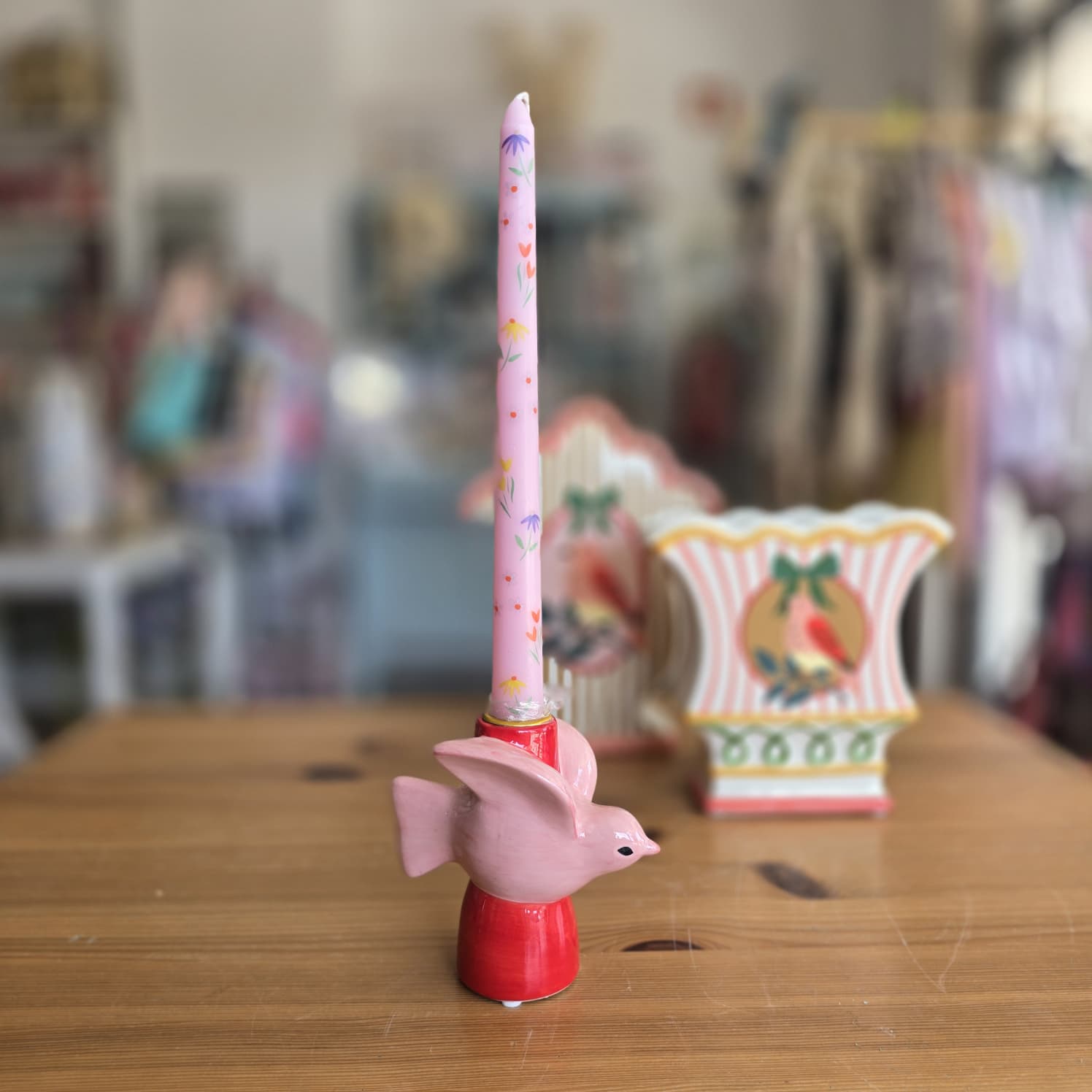 Vela rosa com flores numa base vermelha com figura de pássaro em cerâmica.