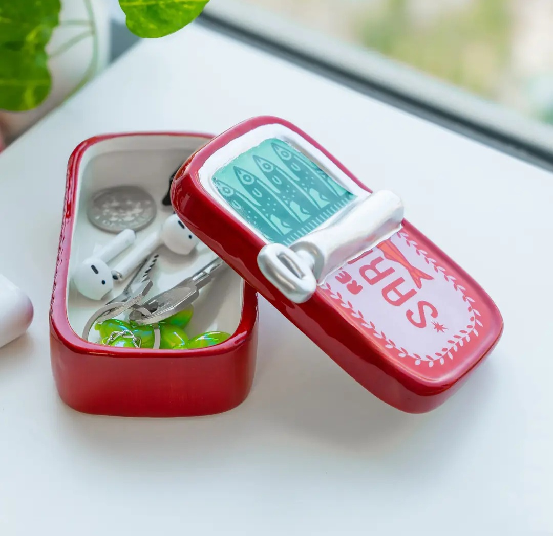 Caixa decorativa vermelha em cerâmica com tampa ilustrada com peixes aberta com chaves e auriculares dentro