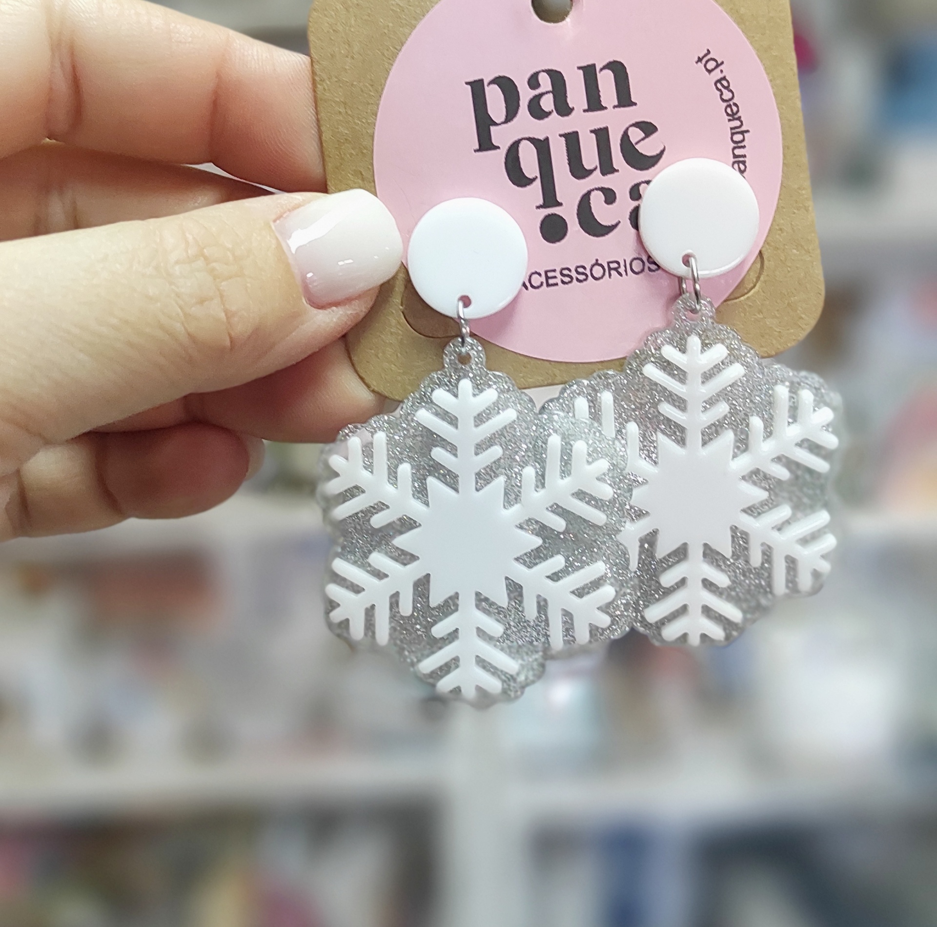 Brincos em forma de floco de neve com glitter prateado e base branca, em cartão rosa da marca panqueca acessórios.
