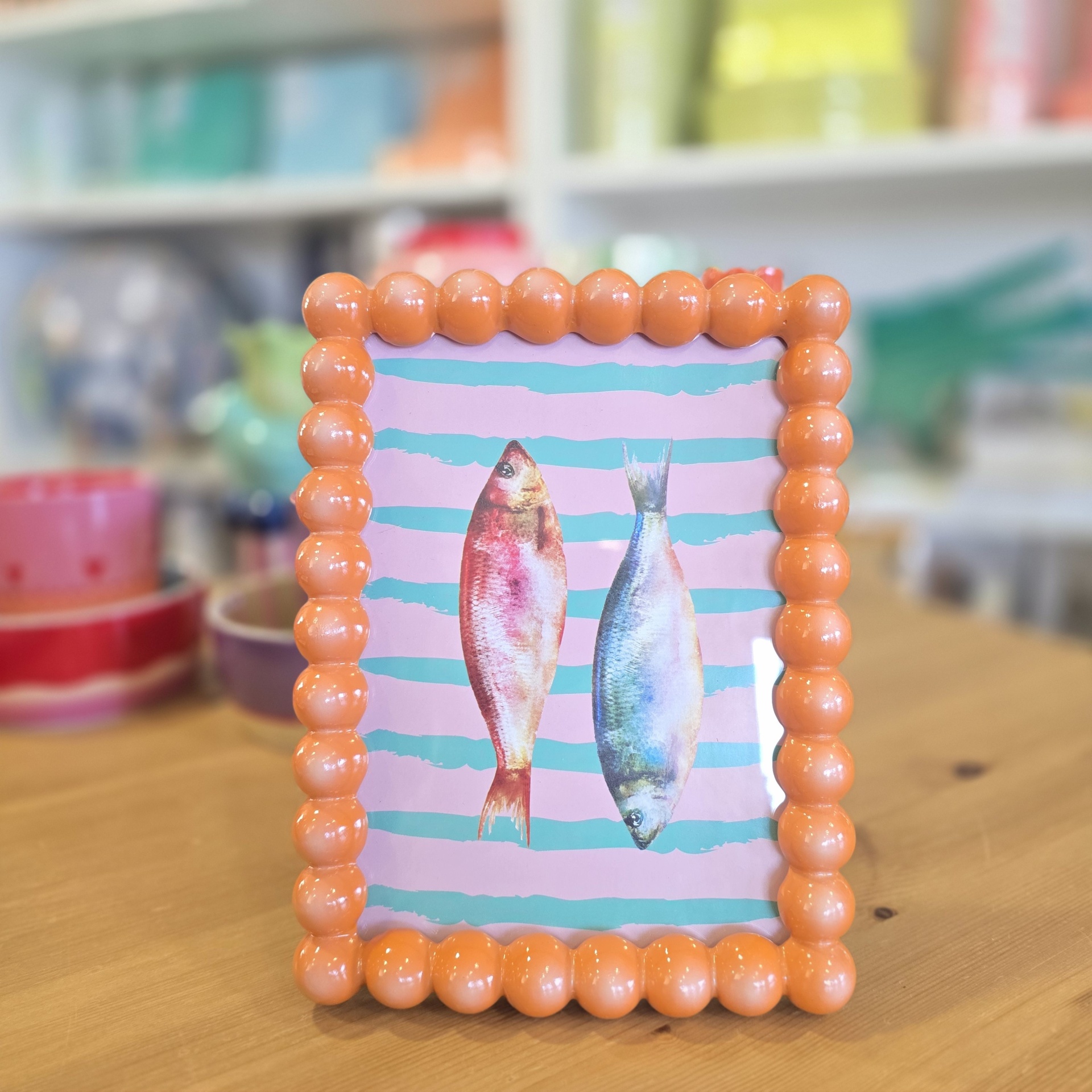 Moldura laranja com bolinhas brilhantes e imagem de dois peixes coloridos