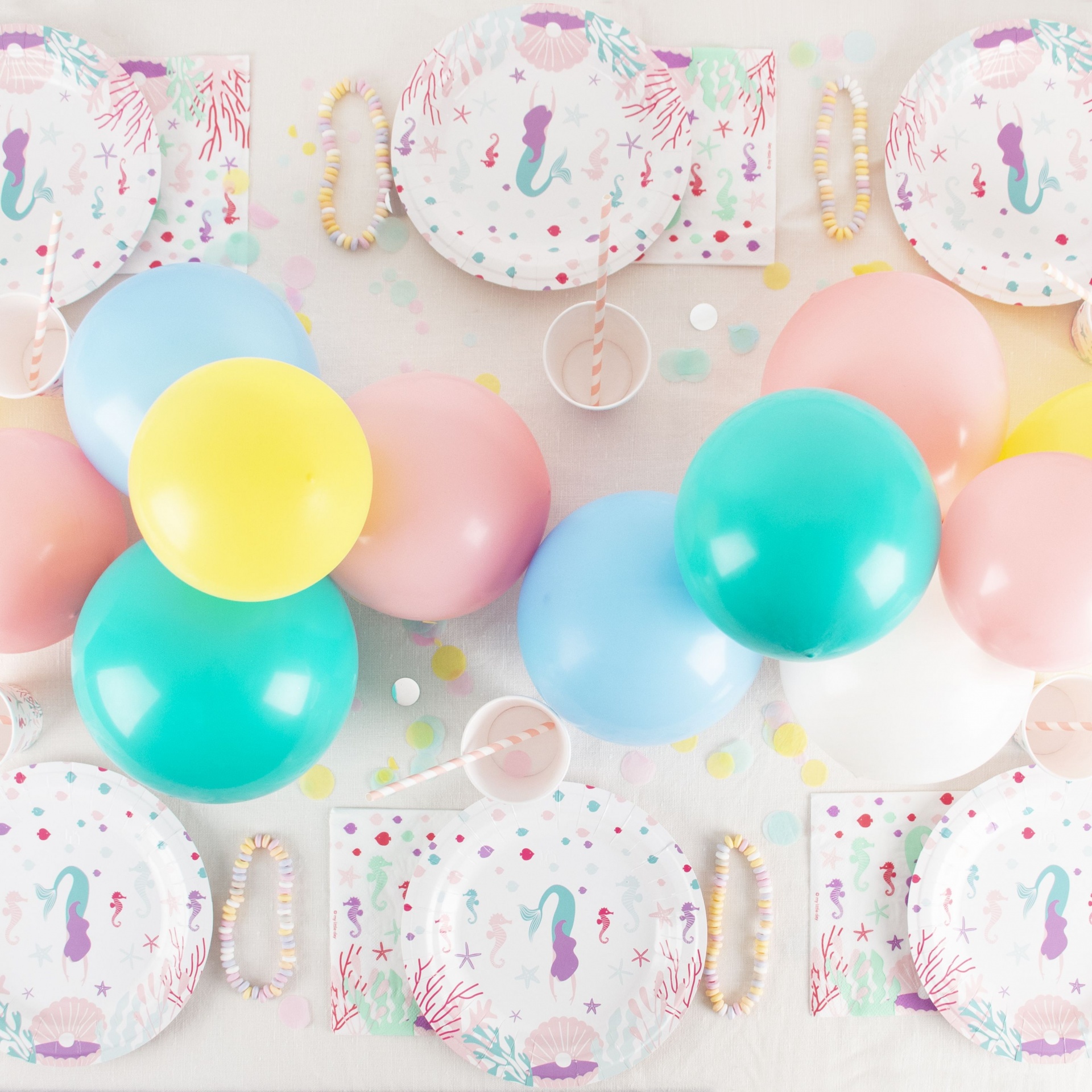 Decoração de festa com pratos de papel de sereia e balões coloridos