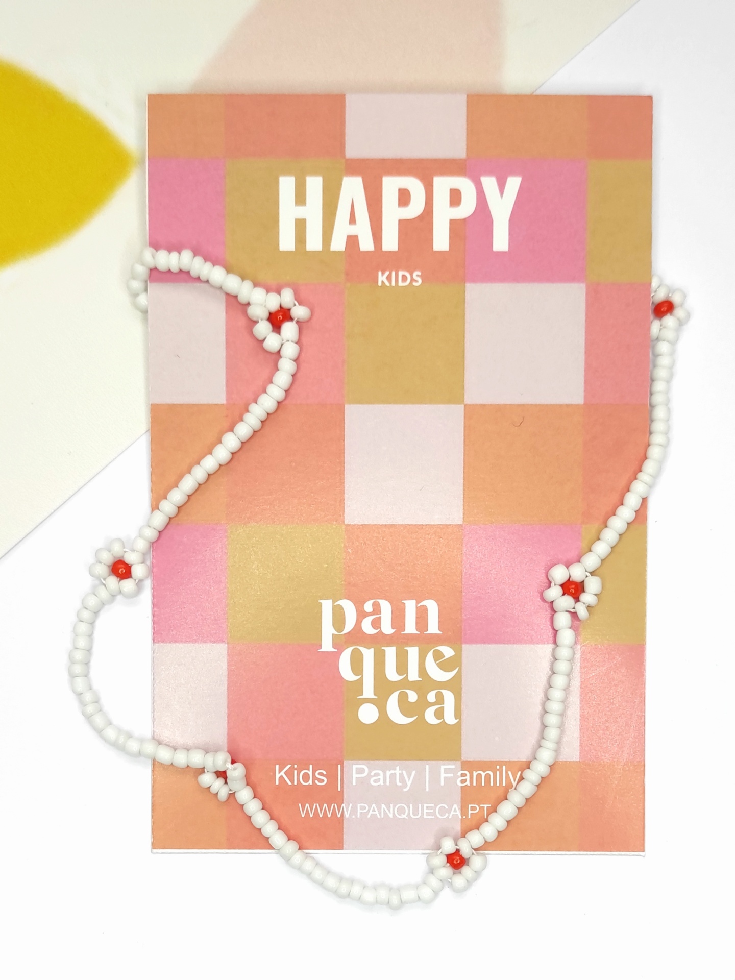 Colar branco com flores vermelhas em cartão quadriculado rosa e bege com texto