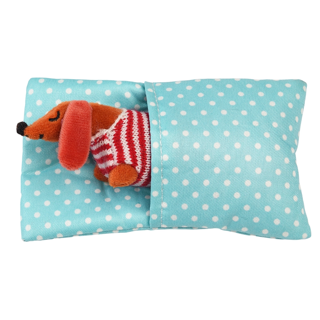 Boneco de peluche de cão com suéter de riscas numa almofada azul com bolinhas brancas