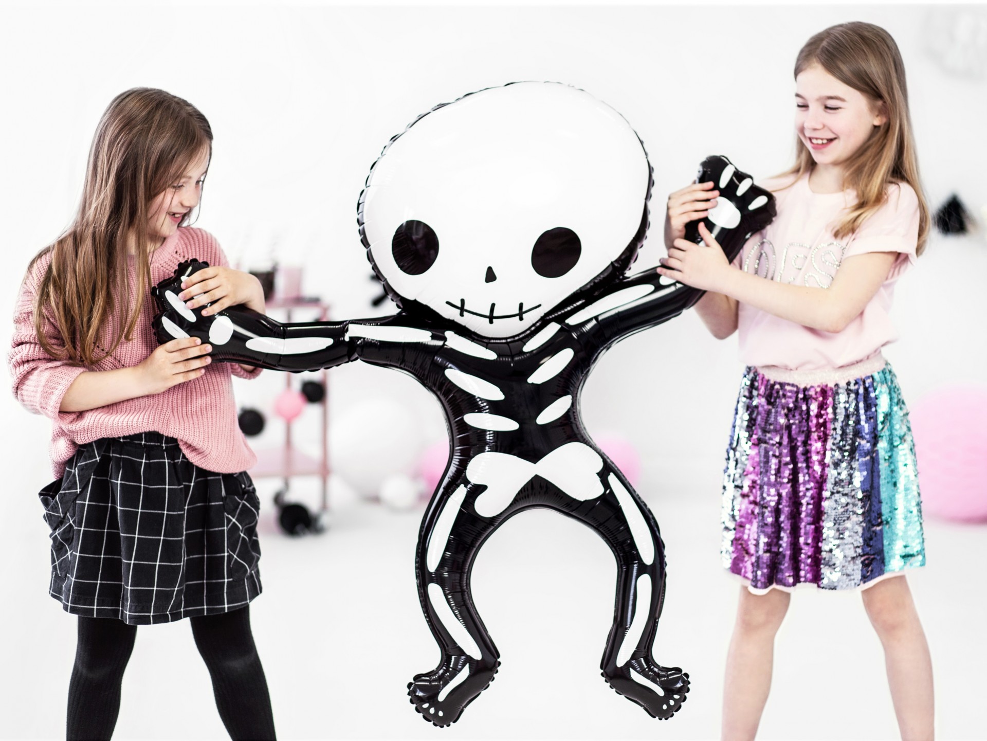 Duas raparigas a divertir-se com um boneco inflável de esqueleto preto e branco