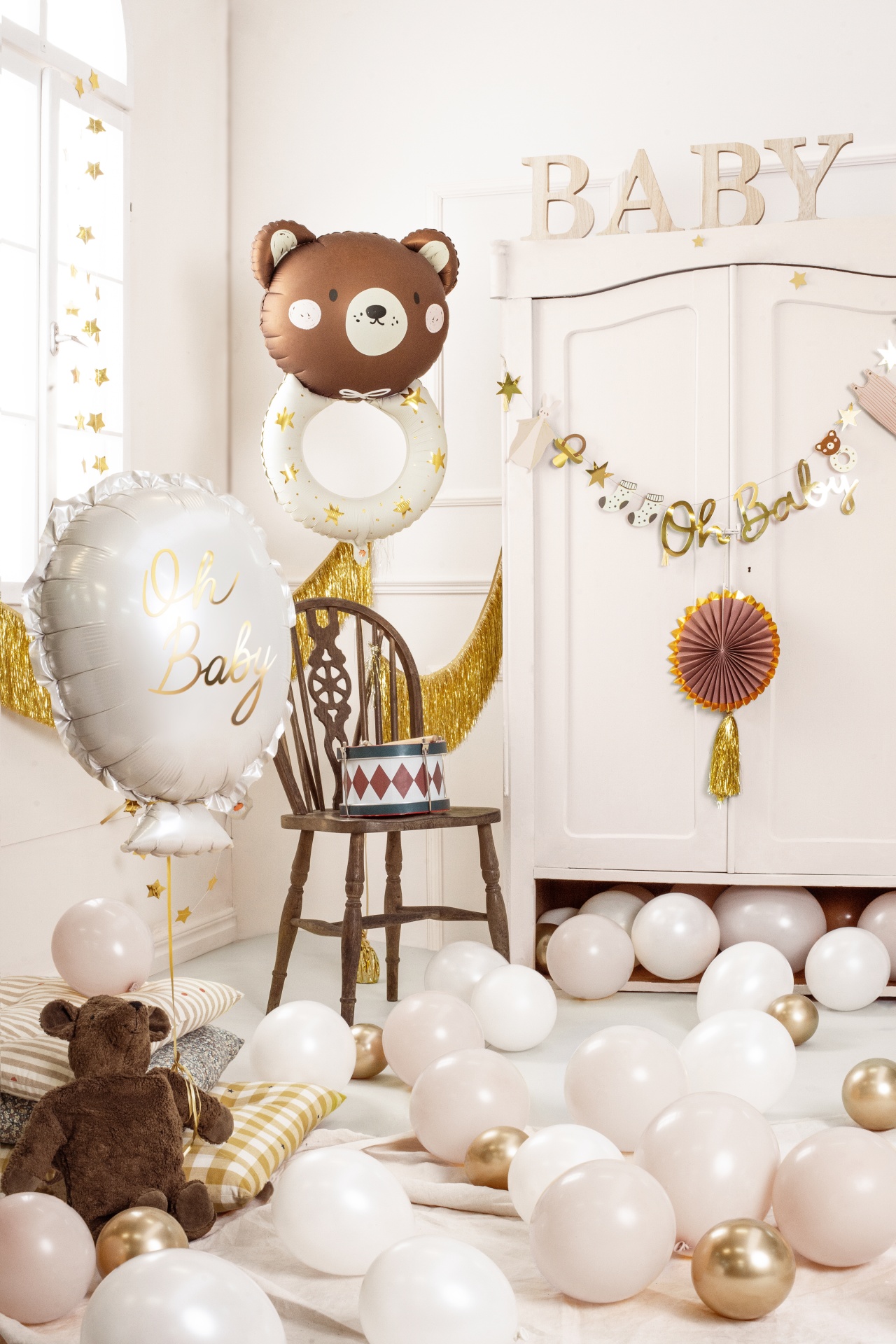 Decoração para chá de bebé com balões, almofadas, ursinho de peluche e cadeira