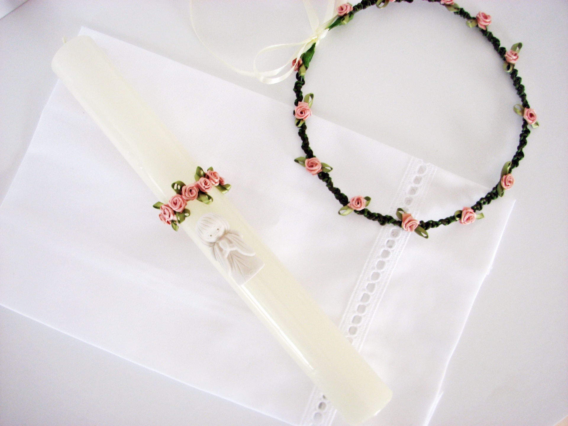 Vela decorada com anjo e coro de flores cor-de-rosa sobre pano branco