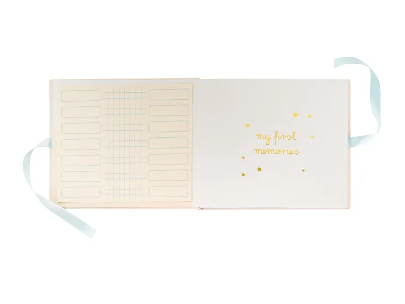 Caderno branco aberto com texto dourado e fita azul clara