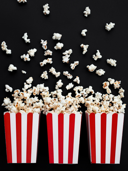 Três caixas vermelhas e brancas cheias de pipocas sobre fundo preto