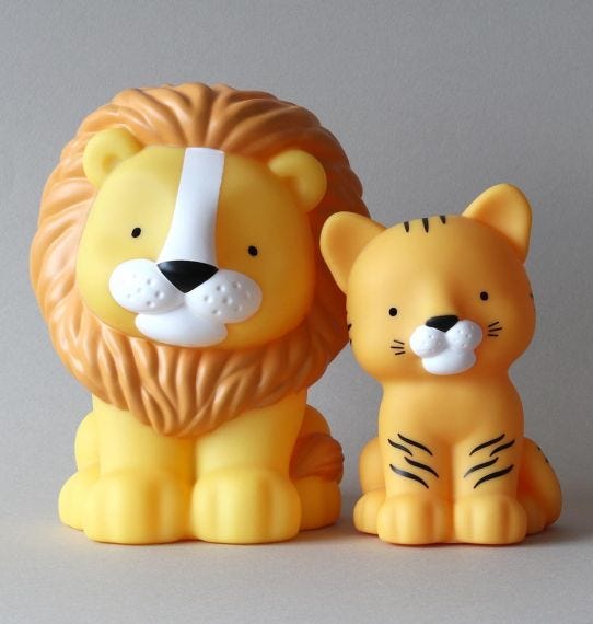 Figuras de leão e tigre amarelos de plástico com expressão amigável.