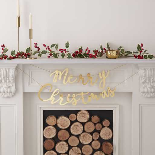 Lareira branca decorada para Natal com troncos, guirlanda de bagas vermelhas, castiçais dourados e pendente dourado 'Merry Christmas'.