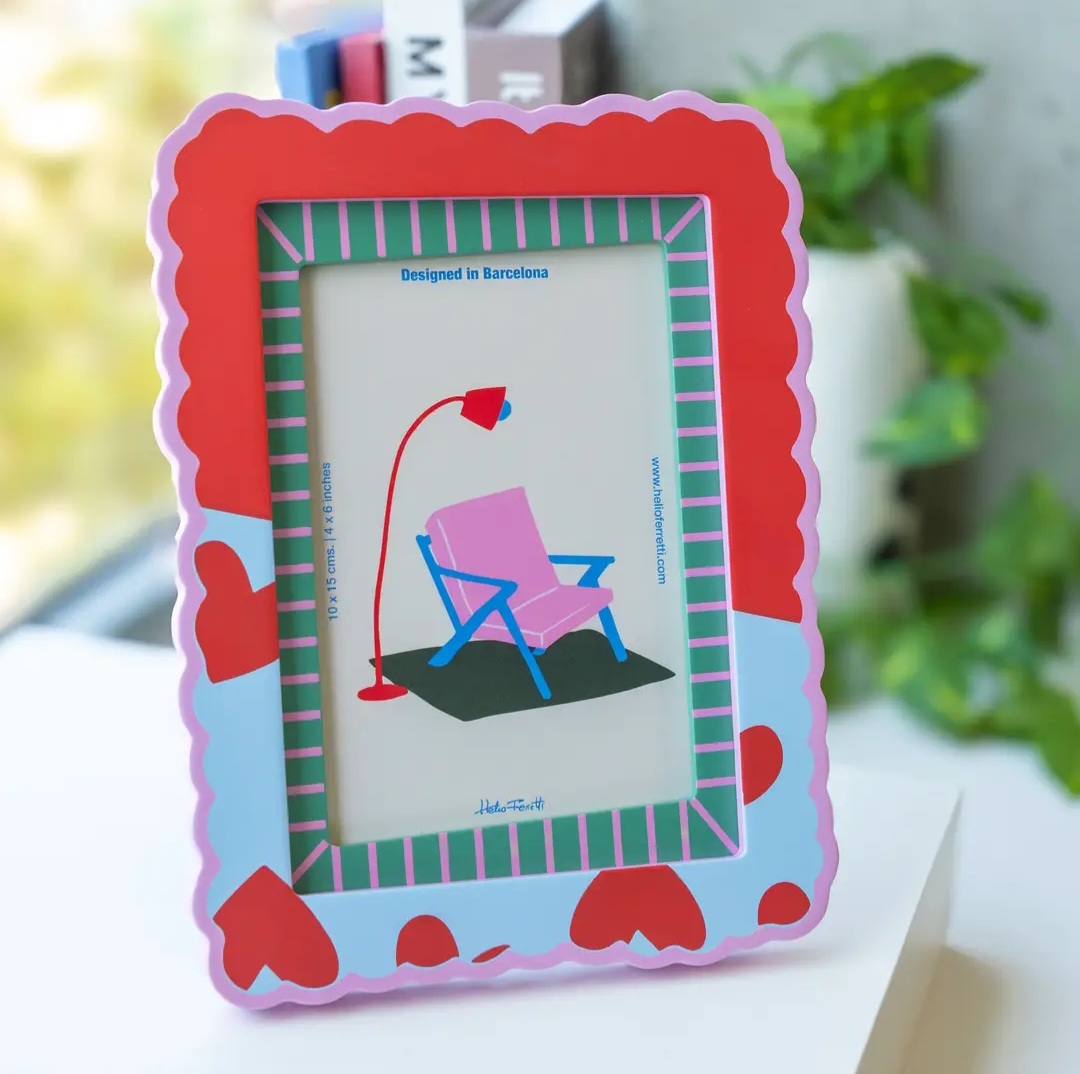 Moldura fotográfica colorida com padrão de corações vermelhos e ilustração de cadeira e candeeiro no centro.