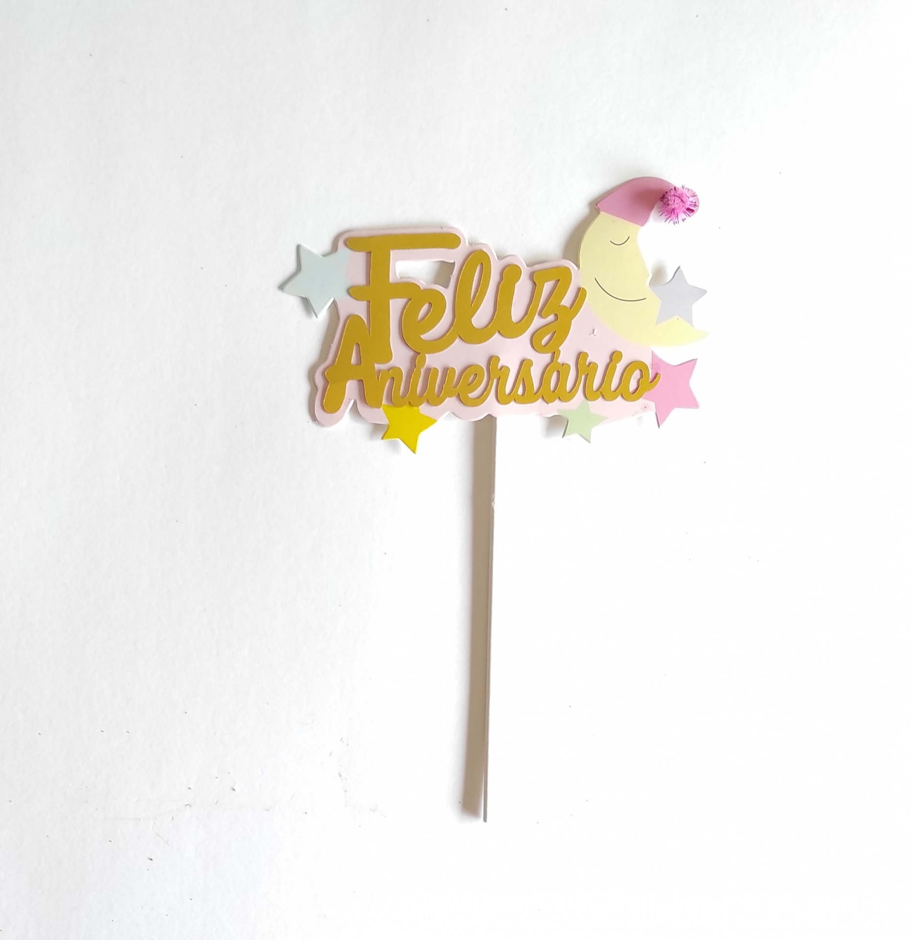Topo de bolo com texto Feliz Aniversário, estrelas coloridas e lua com touca cor-de-rosa