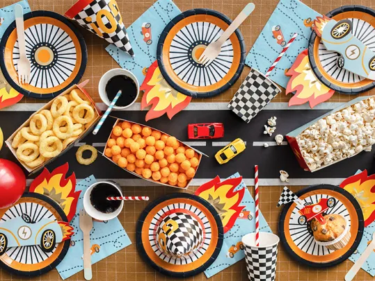 Mesa com decoração de festa temática de corridas, snacks e brinquedos