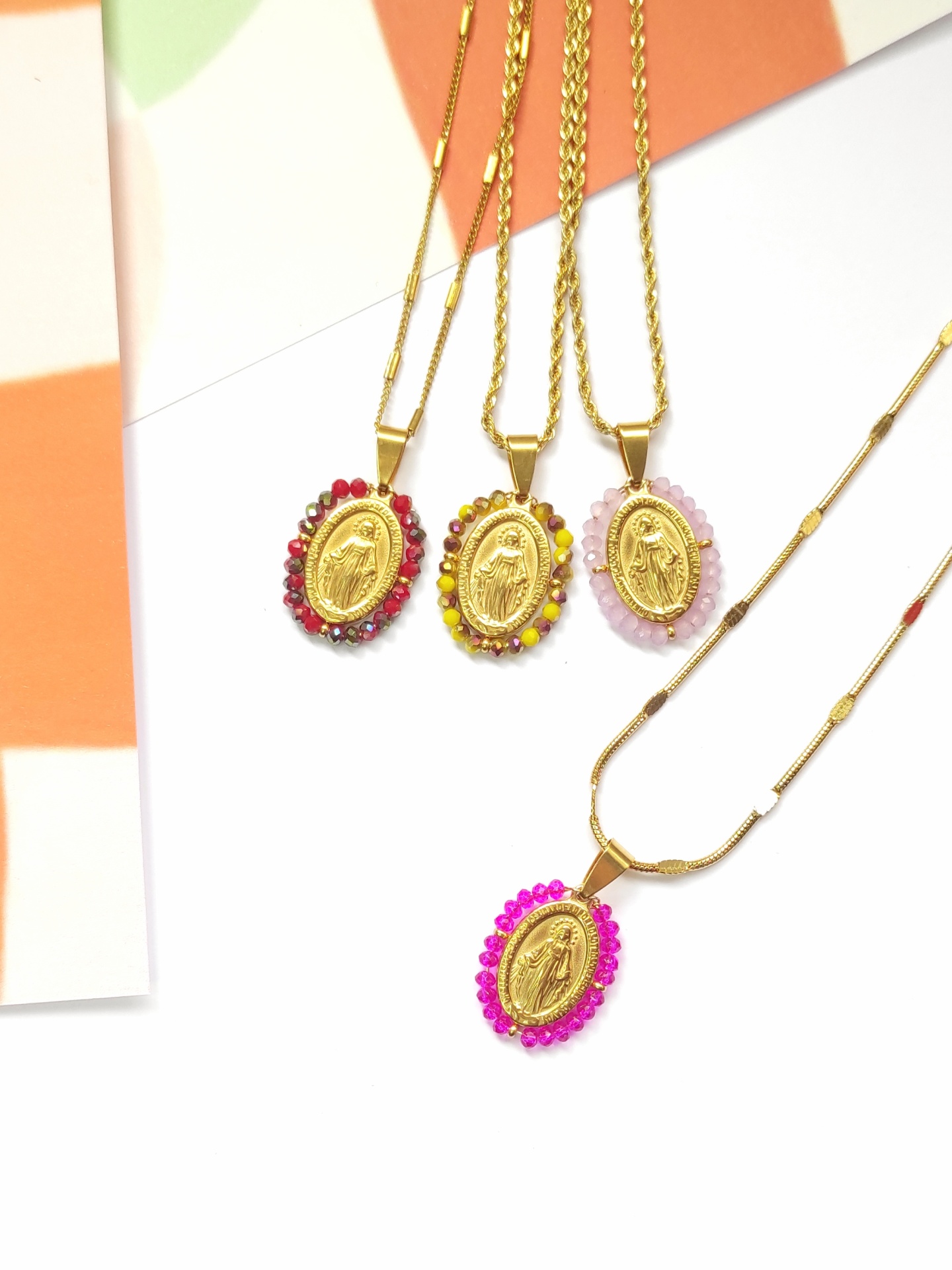 Quatro colares dourados com pendentes ovais e pedras coloridas