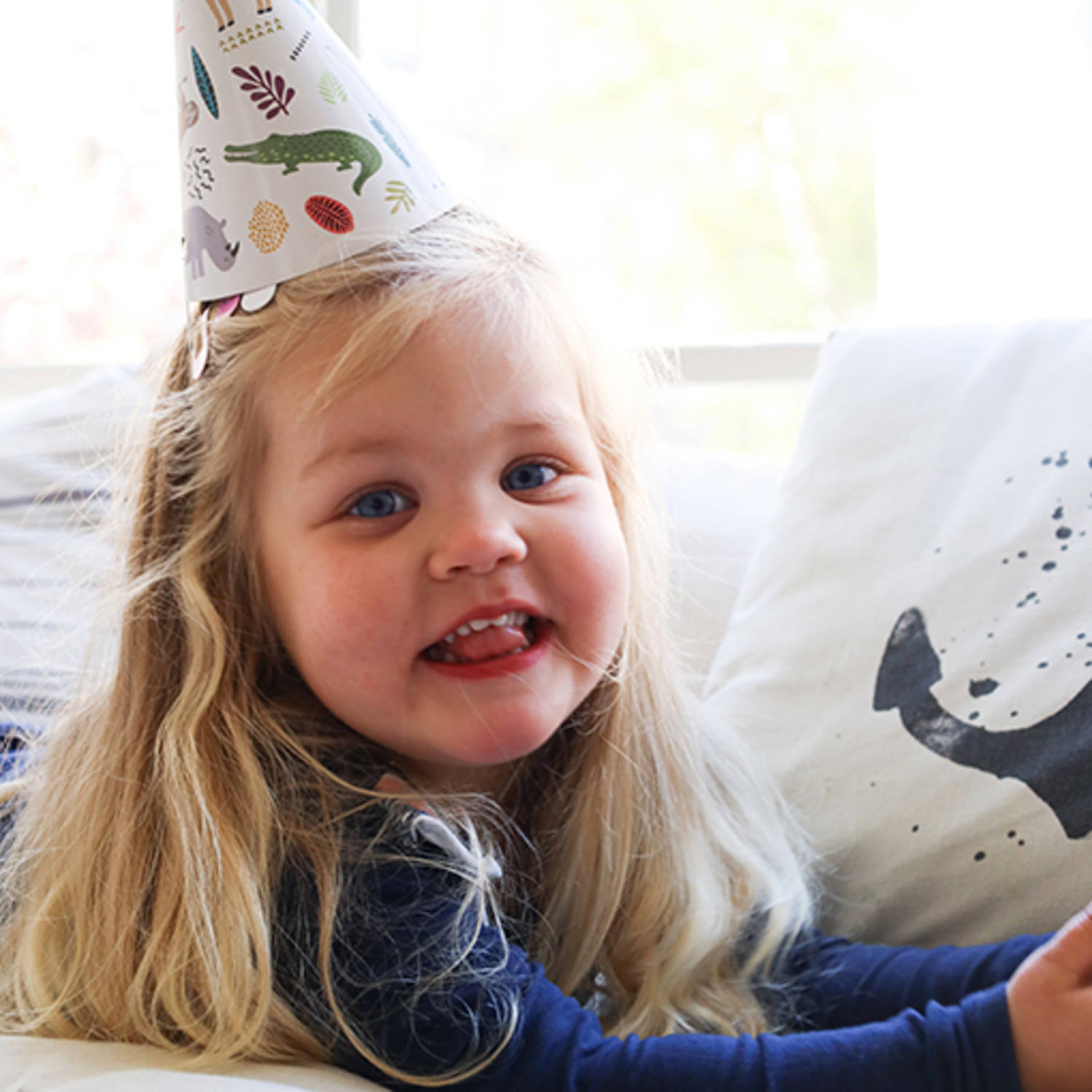 Menina loira com chapéu de festa e almofada com baleia