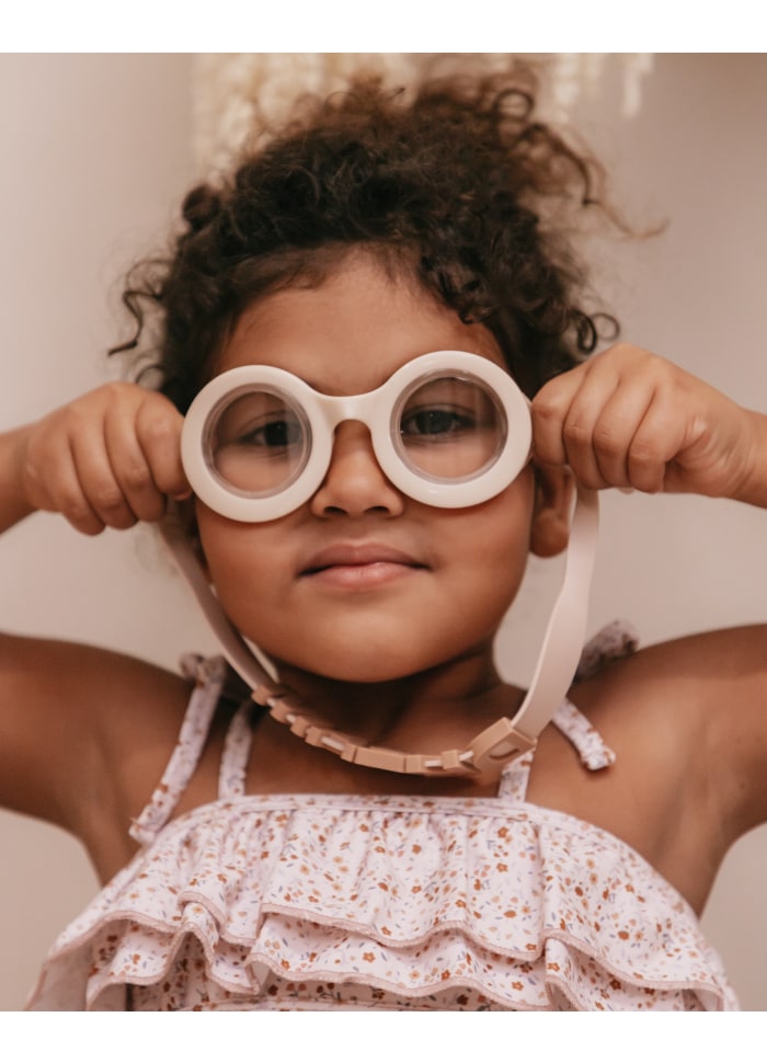 Criança com óculos de mergulho brancos, vestido floral branco com babados