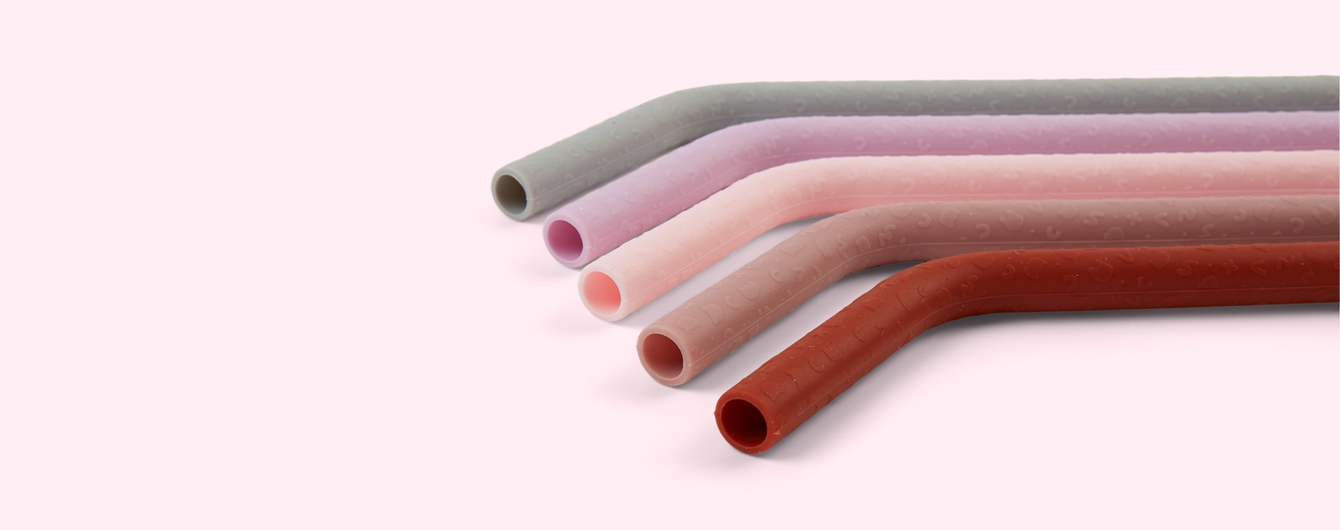 Cinco palhinhas reutilizáveis de silicone coloridas em fundo rosa claro