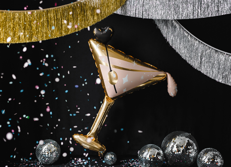 Balão em forma de taça de cocktail dourado com decoração, bolas prateadas e confetes numa festa