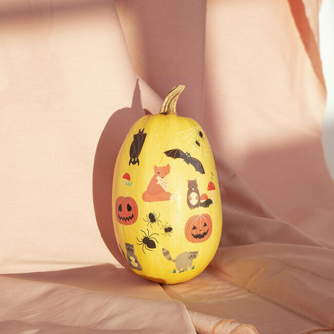 Abóbora amarela decorada com desenhos de Halloween sobre tecido cor de rosa