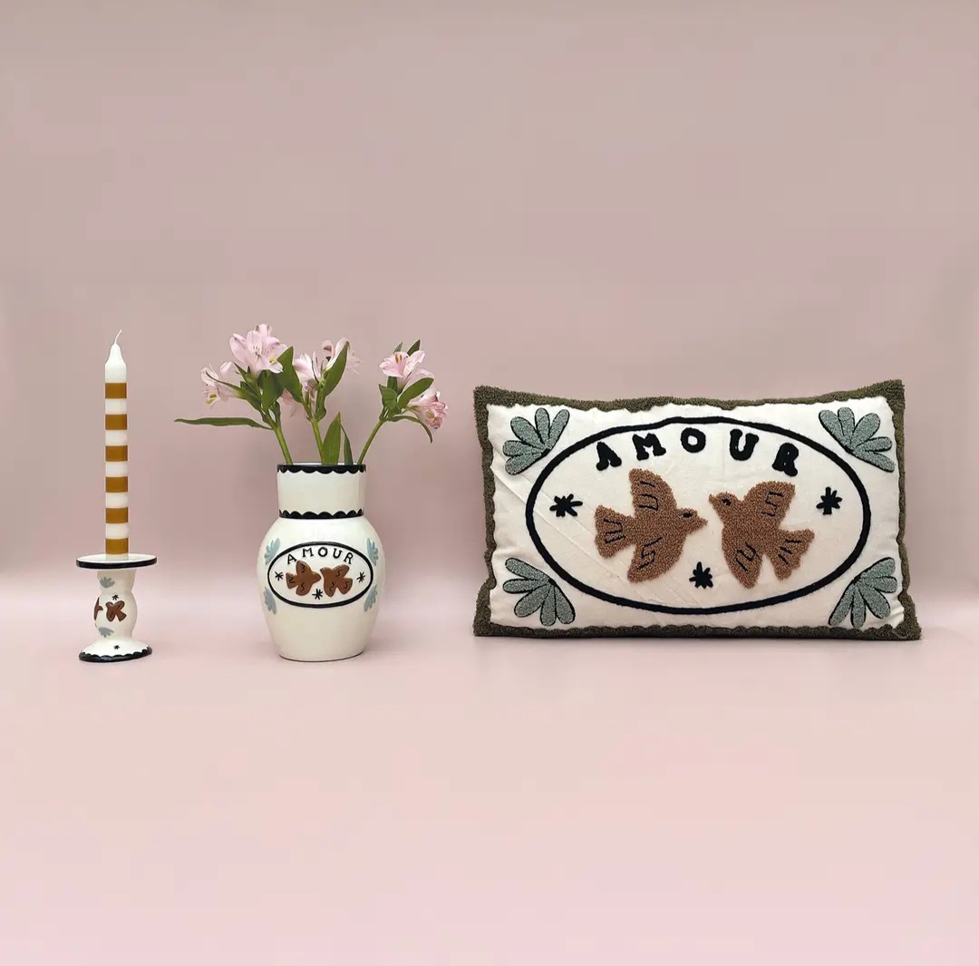 Castiçal com vela, vaso com flores e almofada decorativa com bordado do tema AMOUR