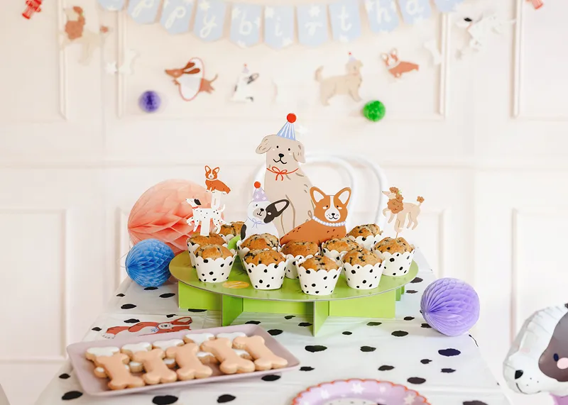 Mesa com mini bolos decorados com desenhos de cachorros e suporte verde