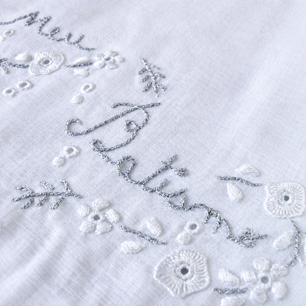 Pano branco bordado com flores e texto Gloria em linha cinzenta e branca