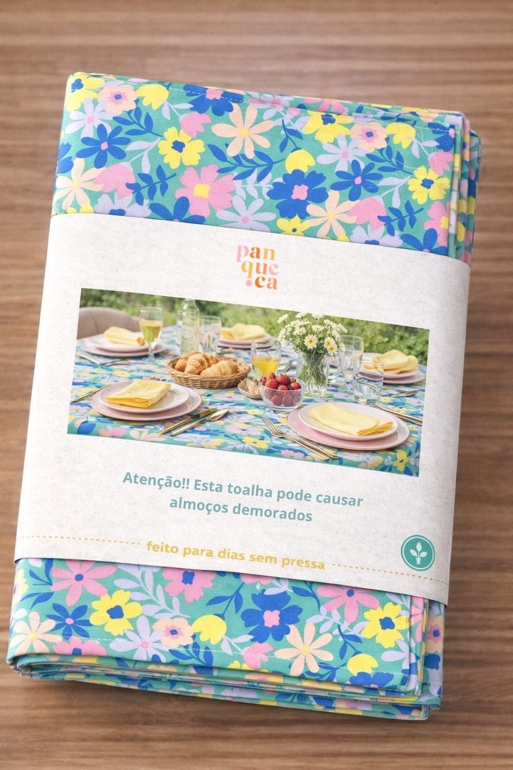 Toalha de mesa floral colorida embalada com faixa de papel e texto em português
