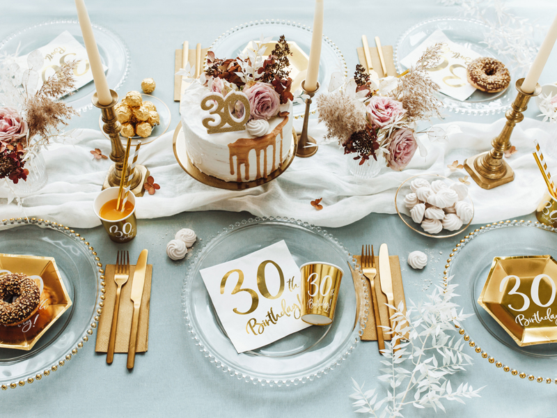 Mesa decorada para aniversário com bolo e artigos de festa no tema dourado e branco
