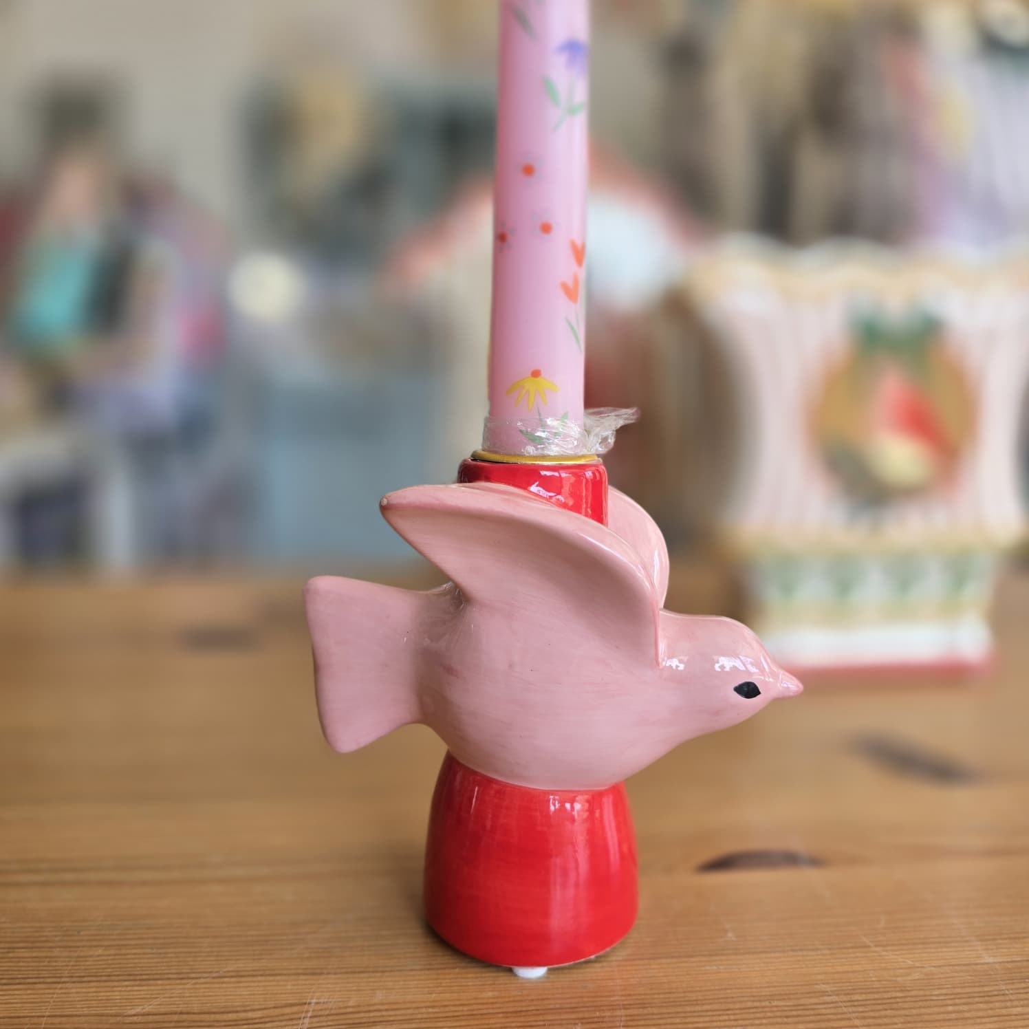 Vela rosa floral em suporte de cerâmica com forma de pássaro rosa e base vermelha