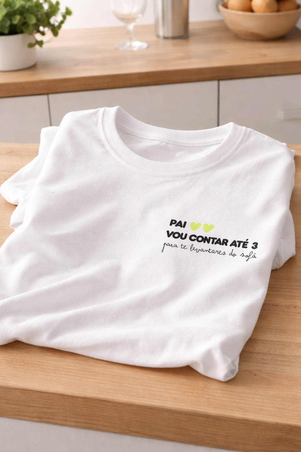 T-shirt branca de algodão com texto gravado, dobrada sobre mesa de madeira