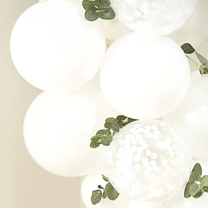 Balões brancos opacos e transparentes com confetes e folhas verdes artificiais