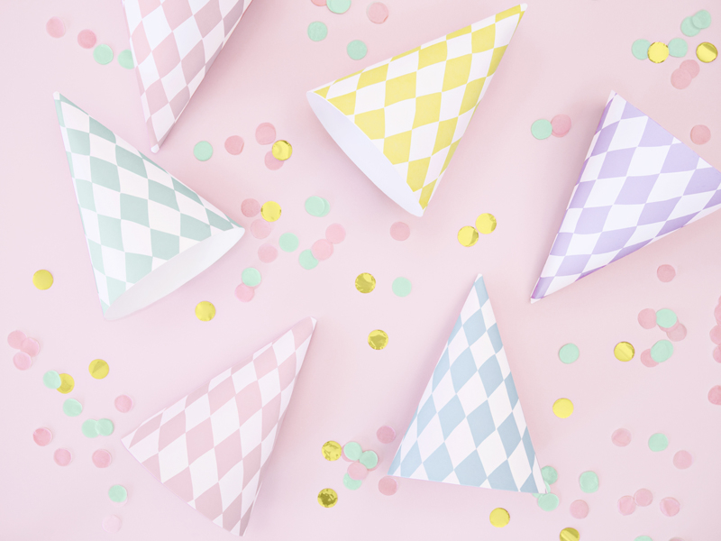 Chapéus de festa xadrez coloridos sobre fundo rosa com confetis